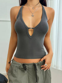 Person wearing a gray halter top and green pants indoors