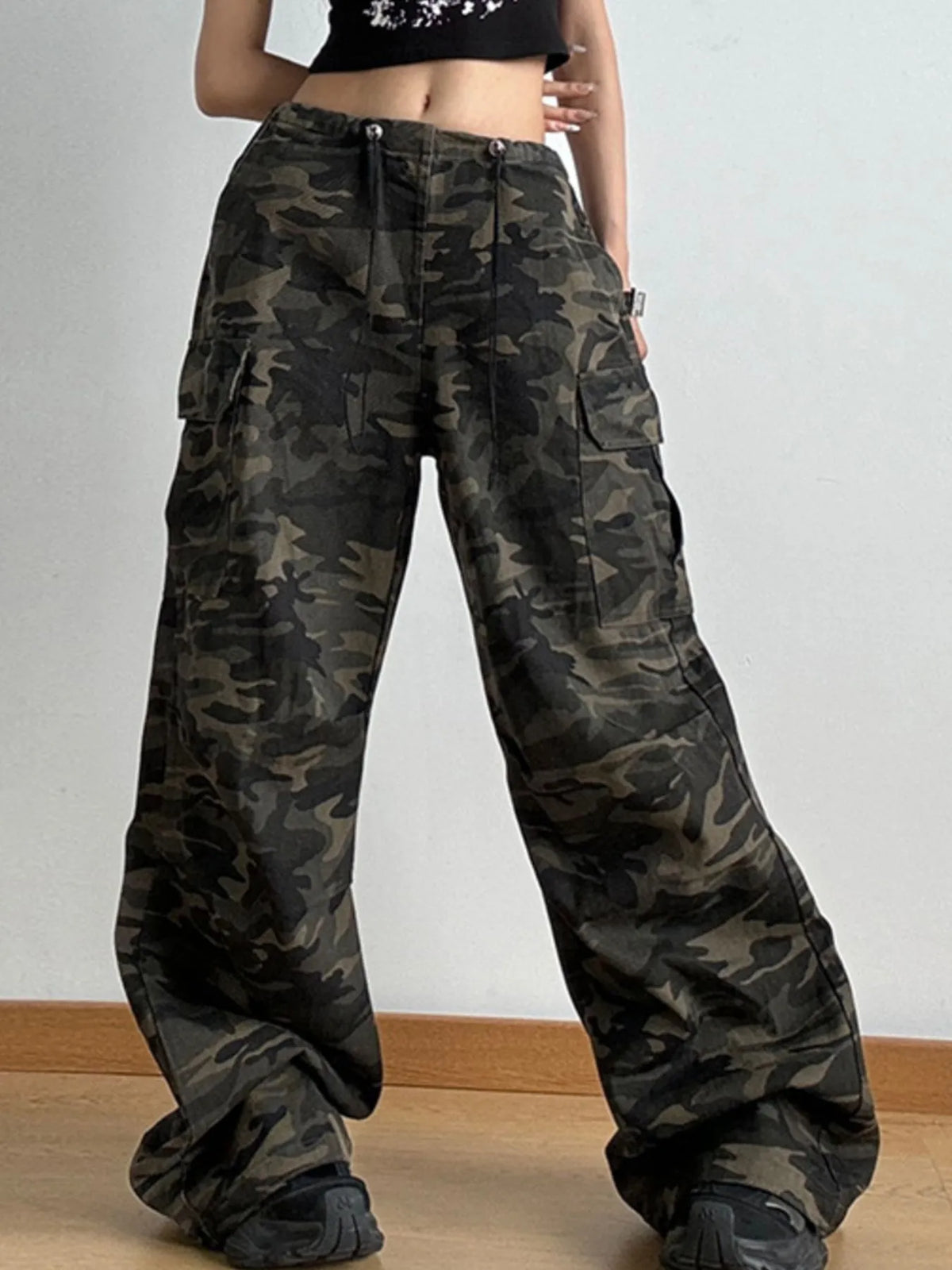 Camouflage pants worn by a person on a plain background