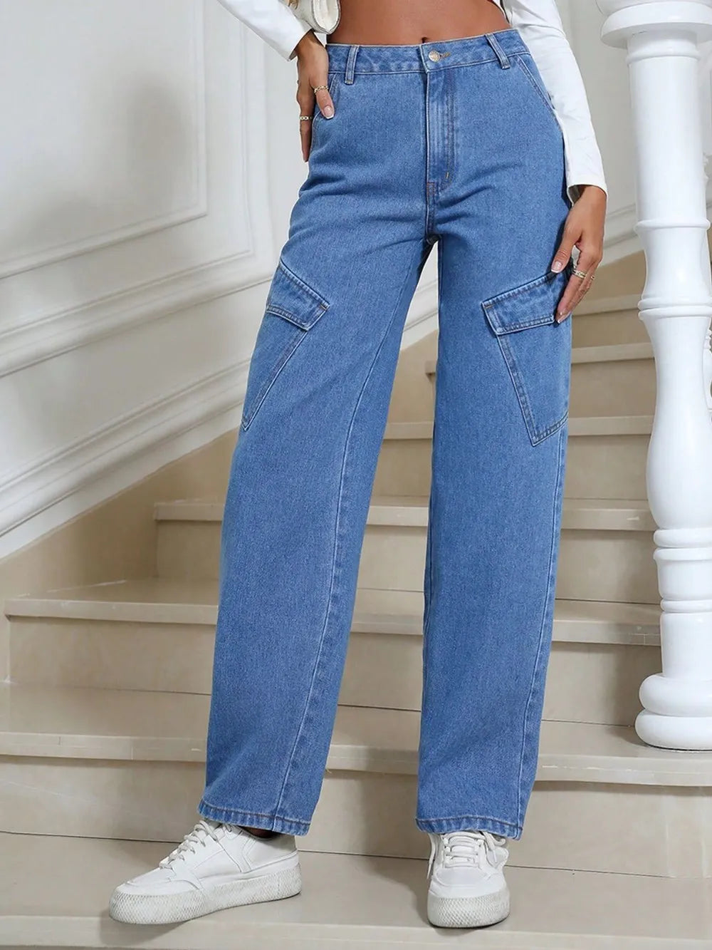 Person wearing blue jeans and white sneakers standing on a staircase.