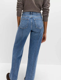 Person wearing blue jeans and a brown sweater on a white background