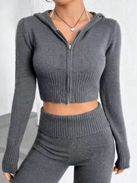 Person wearing a gray zip-up hoodie and matching pants on a white background