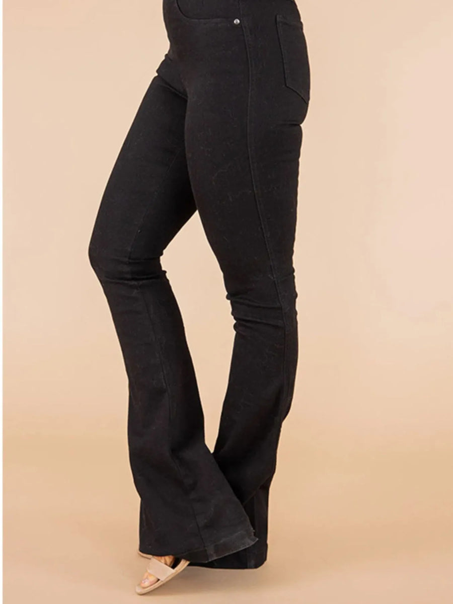 Black bell-bottom pants on a beige background