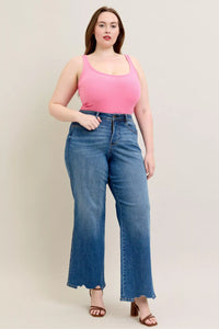 Woman wearing a pink top and blue jeans against a plain background