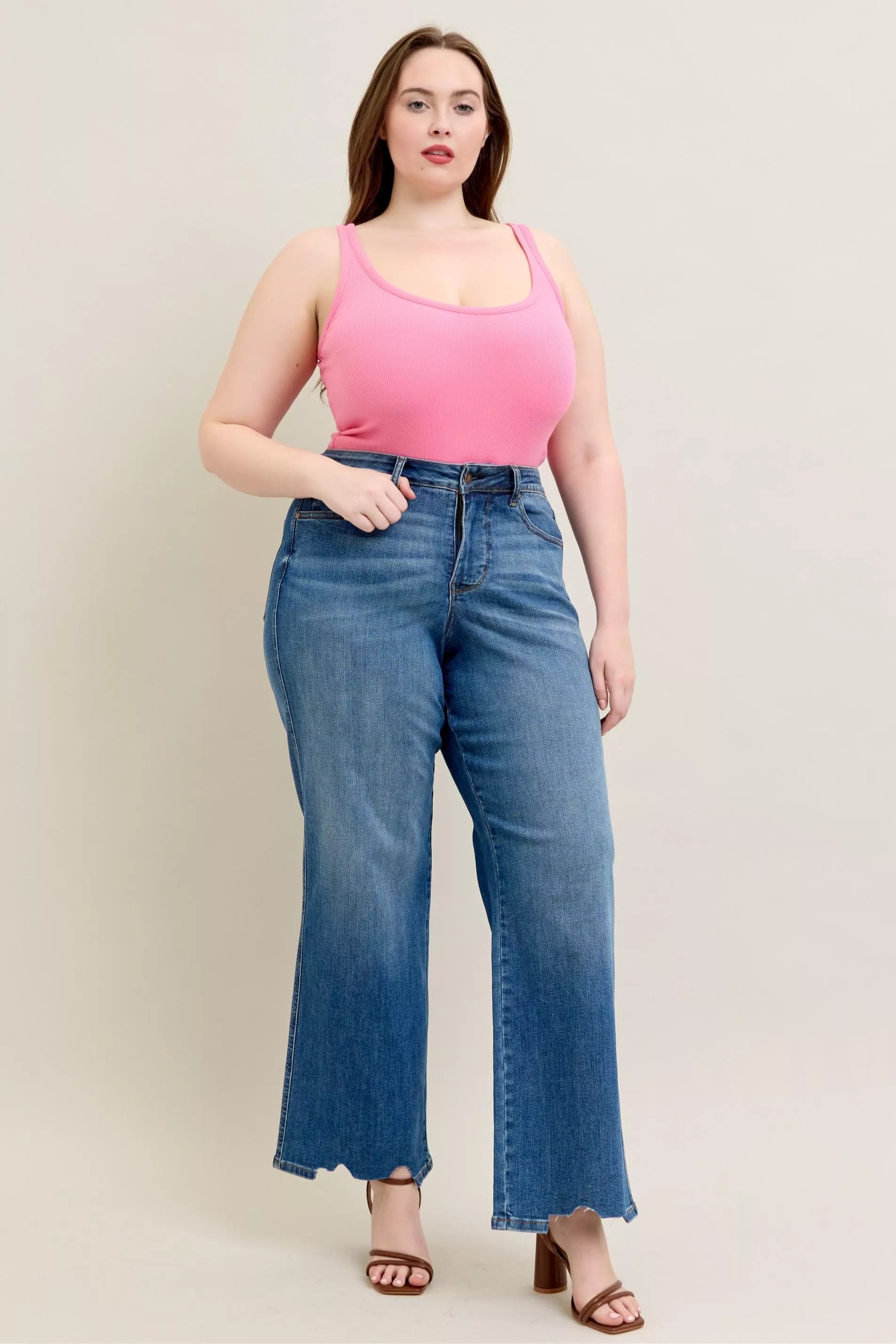 Woman wearing a pink top and blue jeans against a plain background
