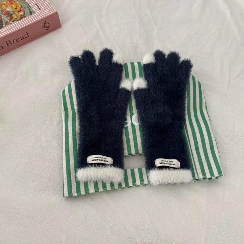 Pair of black fluffy gloves with white tips on a green and white striped box.