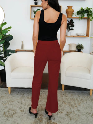 Woman wearing a black top and red pants in a living room setting