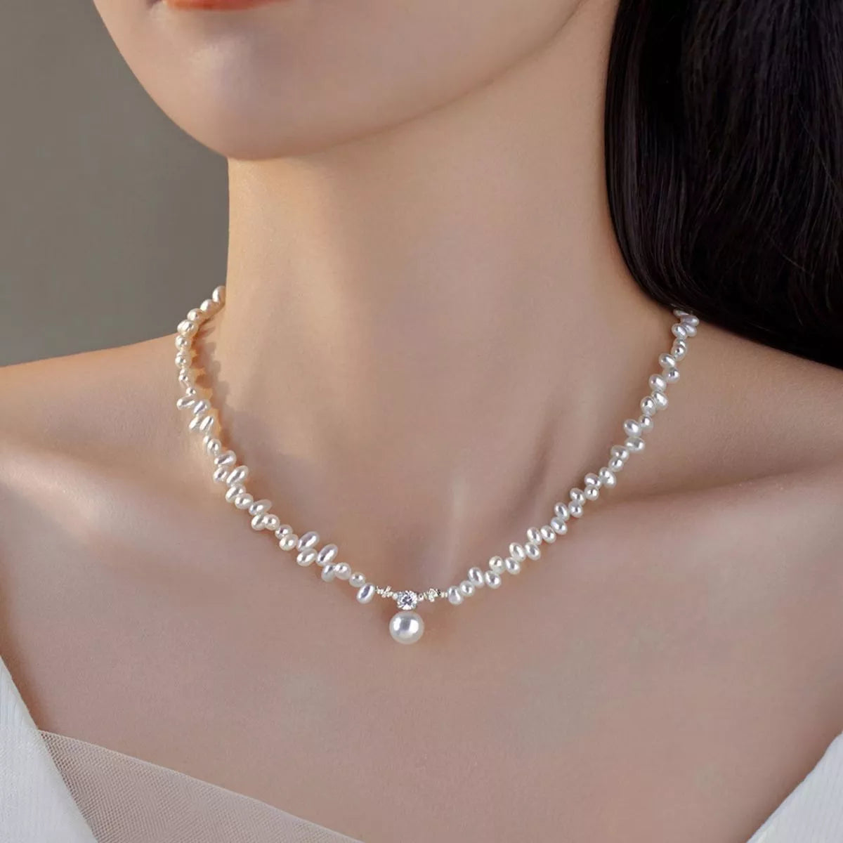 Pearl necklace worn by a model with a neutral background