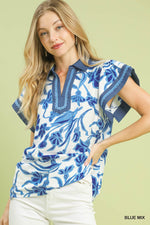 Woman wearing a blue and white floral patterned top on a light green background