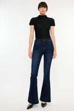 Person wearing a black turtleneck and dark blue flared jeans on a white background