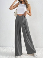 Woman wearing a white crop top and gray wide-leg pants against a white background