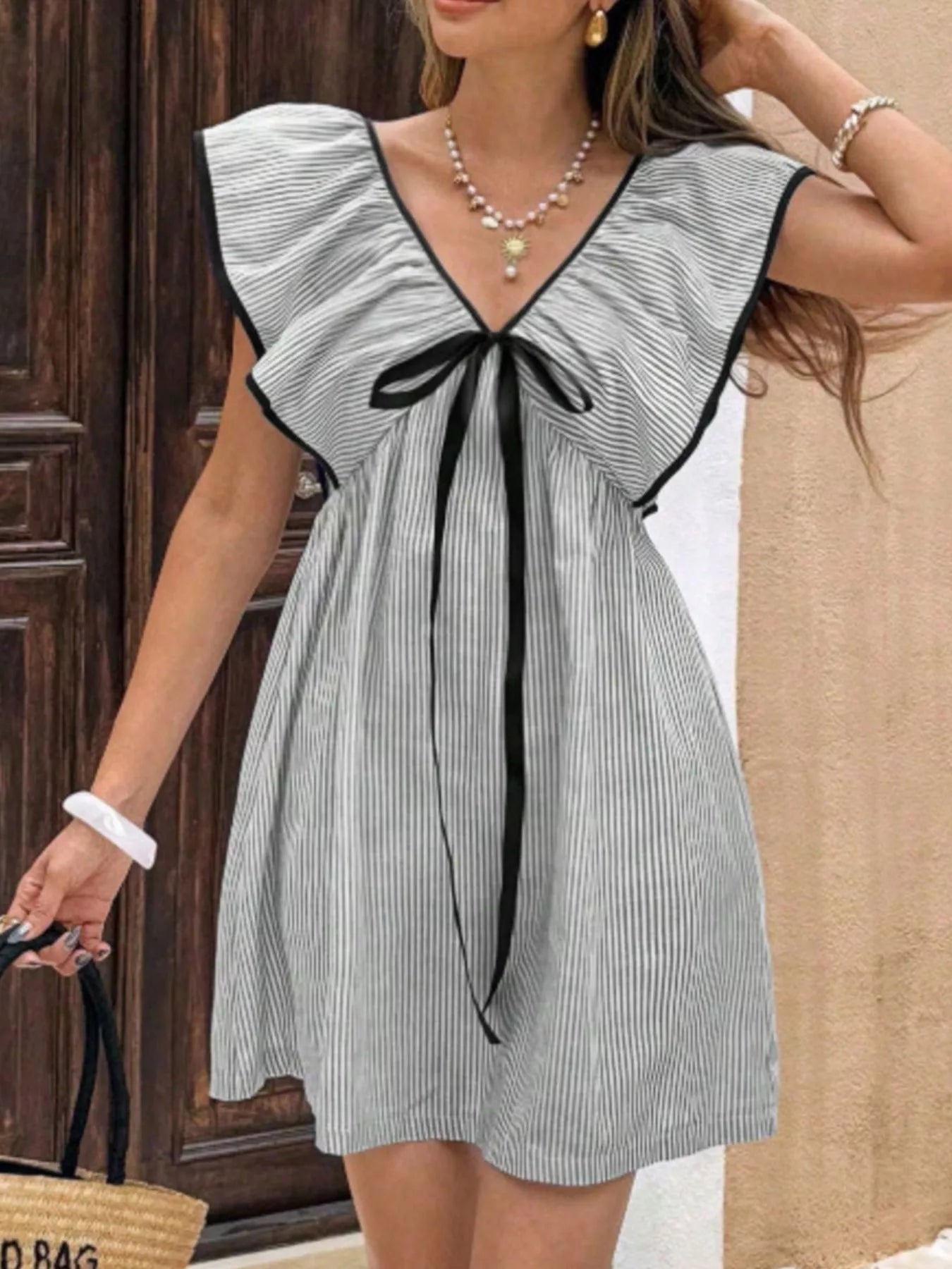 Woman wearing a black and white striped dress with a bow detail.
