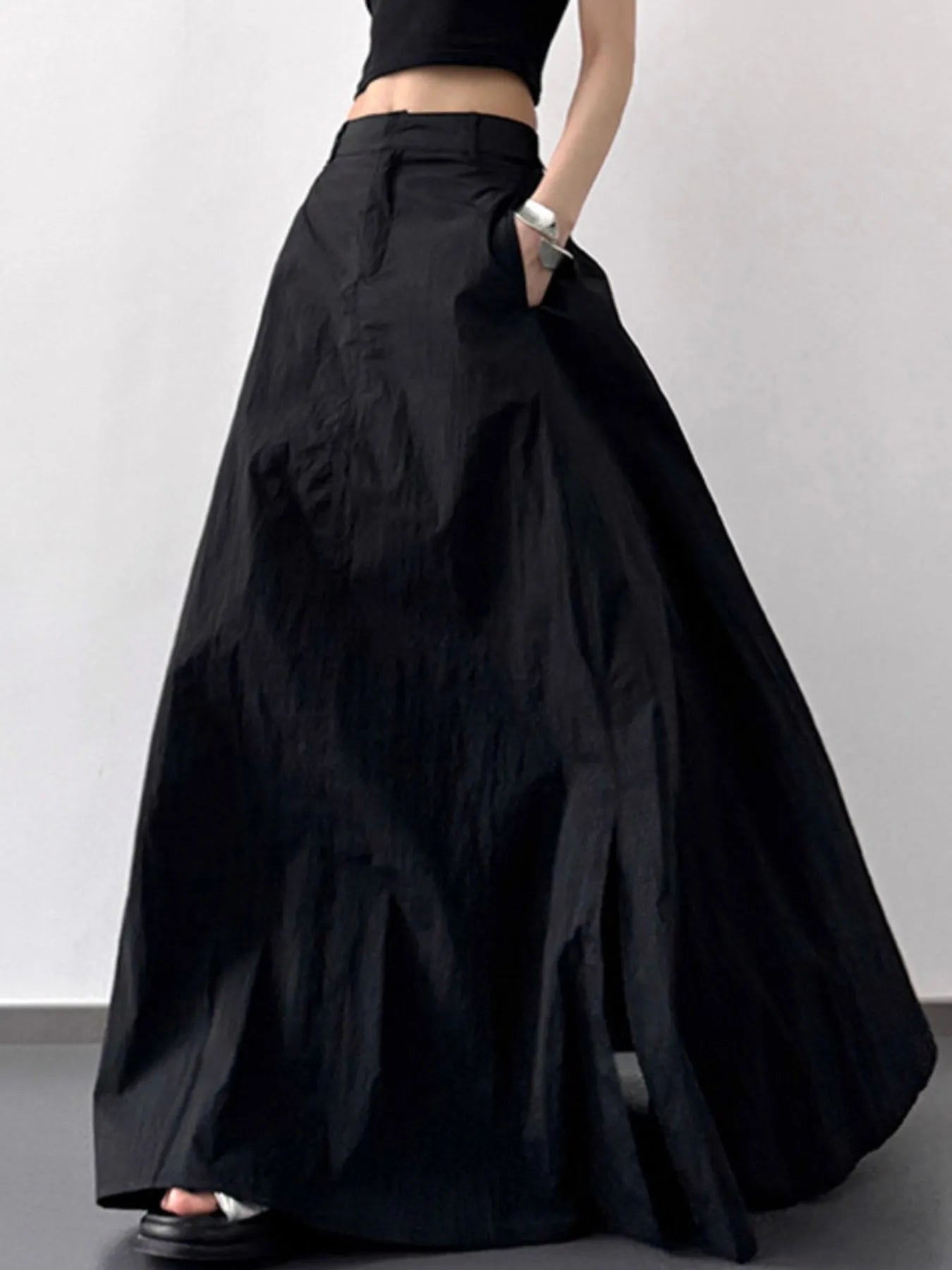 Black long skirt worn by a person on a plain background