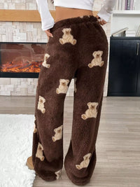 Brown fuzzy pants with teddy bear patterns worn by a person in a home setting.