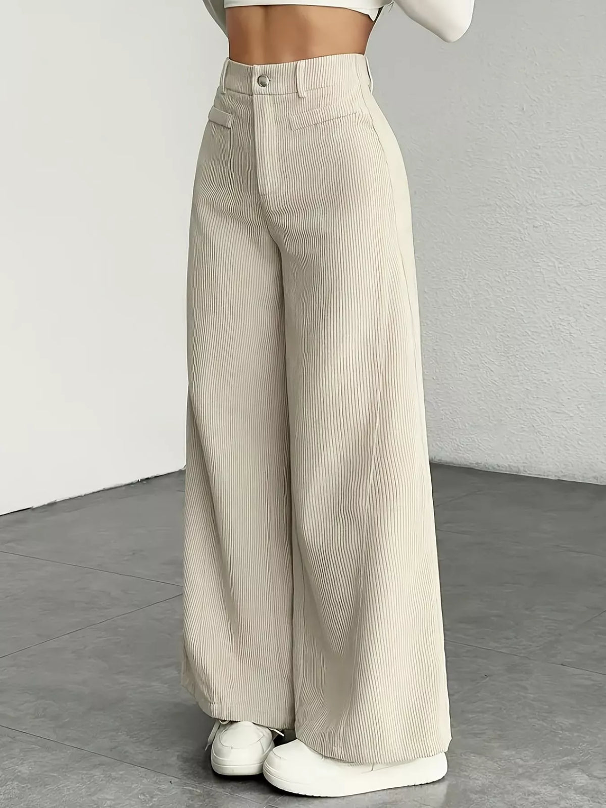 Beige wide-leg pants worn by a person on a neutral background