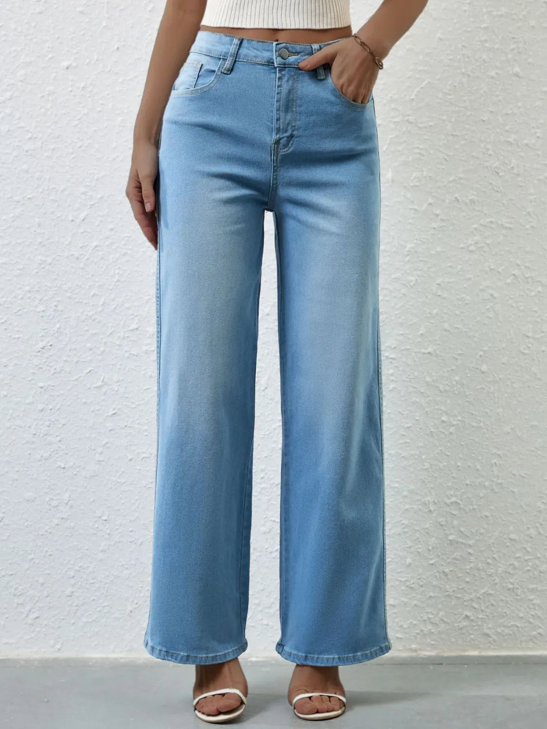 Light blue jeans worn by a person against a plain background