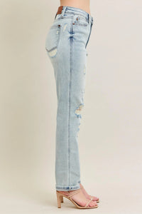 Light blue distressed jeans worn by a person on a beige background