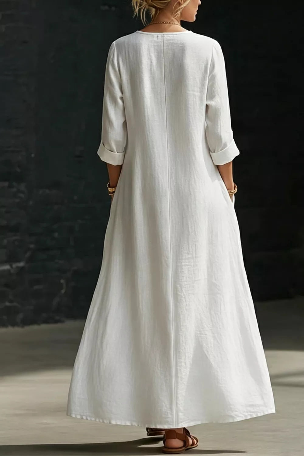 Person wearing a long white dress against a dark background