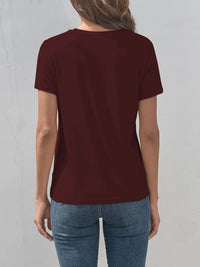 Person wearing a maroon t-shirt and blue jeans against a light gray background