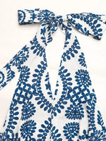 White garment with blue floral pattern and bow detail on a white background