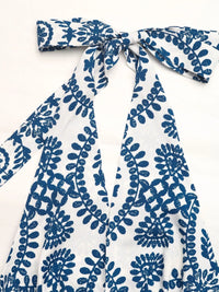 White garment with blue floral pattern and bow detail on a white background