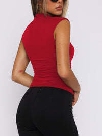 Person wearing a red sleeveless top and black pants on a white background