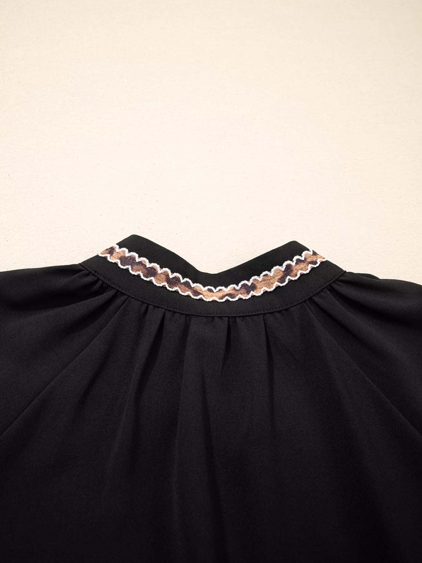 Black dress with lace trim on a beige background