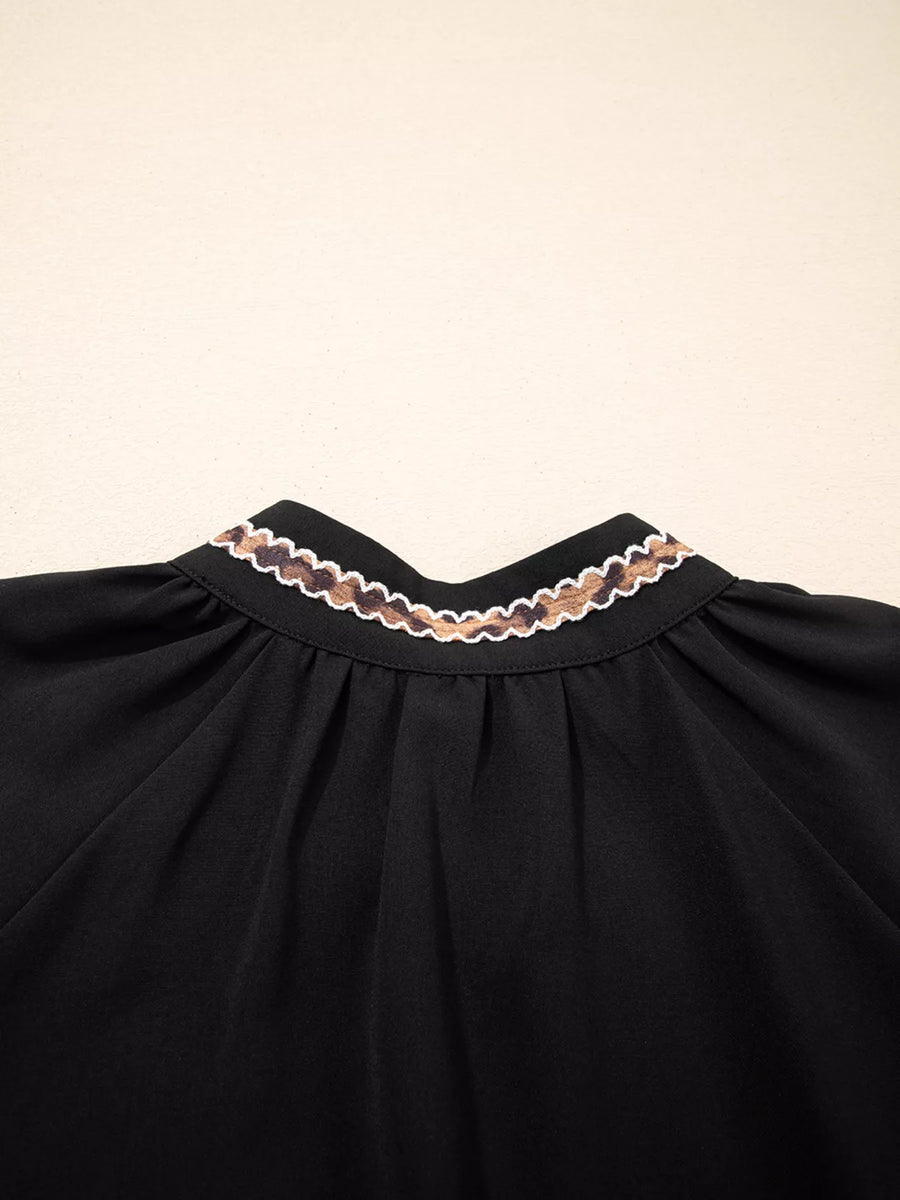 Black dress with lace trim on a beige background