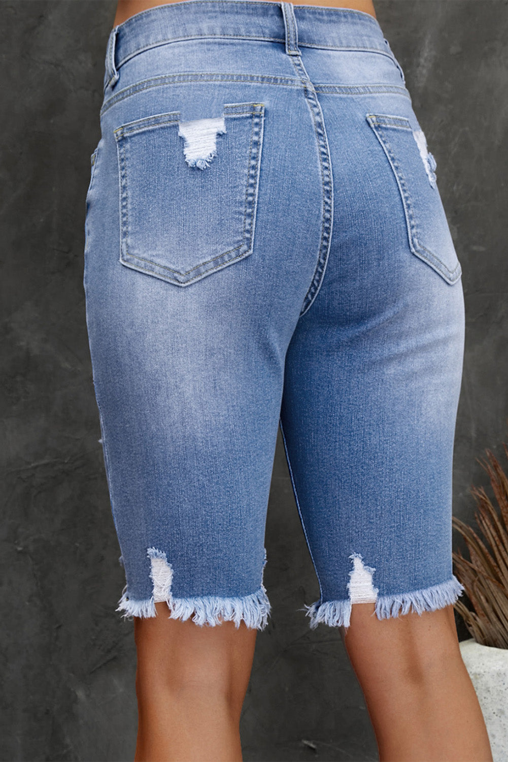 Blue denim shorts with frayed edges on a dark background