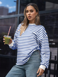 Woman in a blue and white striped sweater holding a green smoothie.