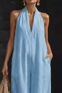 Woman wearing a light blue halter jumpsuit against a dark background