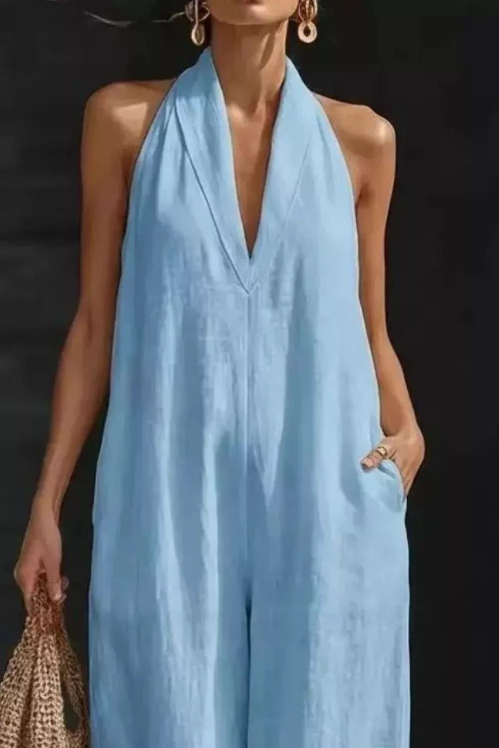 Woman wearing a light blue halter jumpsuit against a dark background