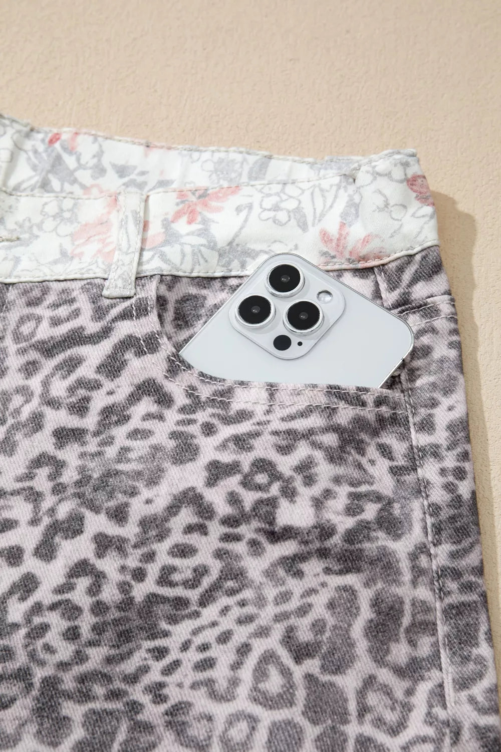 Leopard print shorts with a floral waistband on a beige background
