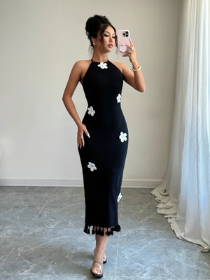 Woman wearing a black dress with white floral patterns taking a mirror selfie.