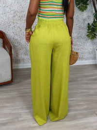 Person wearing a colorful top and bright green pants in an indoor setting.