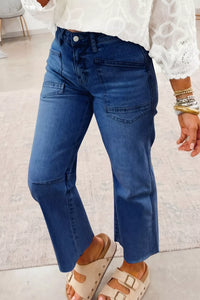 Person wearing blue jeans and white lace top on a light background