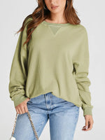 Woman wearing a green ribbed sweater and blue jeans on a white background