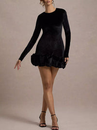 Black long-sleeve dress with ruffled skirt on a beige background