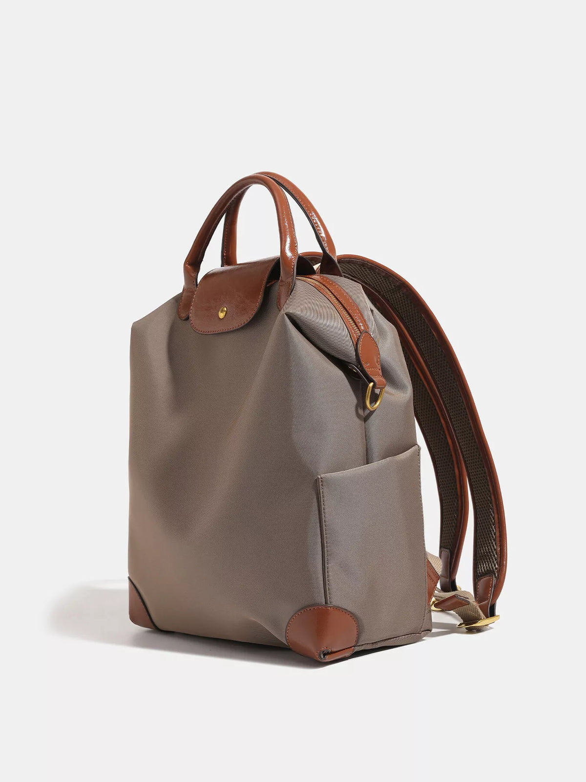 A taupe gray nylon backpack with brown leather handles, trim, and soles, shown from a three-quarter angle on a light gray background.