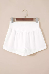 White shorts on a hanger against a beige background