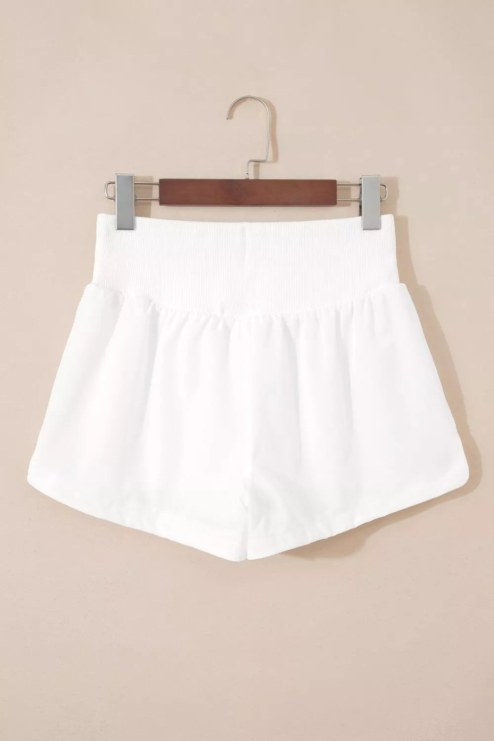 White shorts on a hanger against a beige background