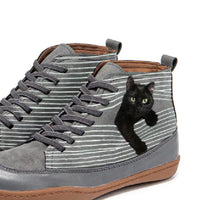 Gray high-top sneakers with a black cat peeking out from one of them on a white background
