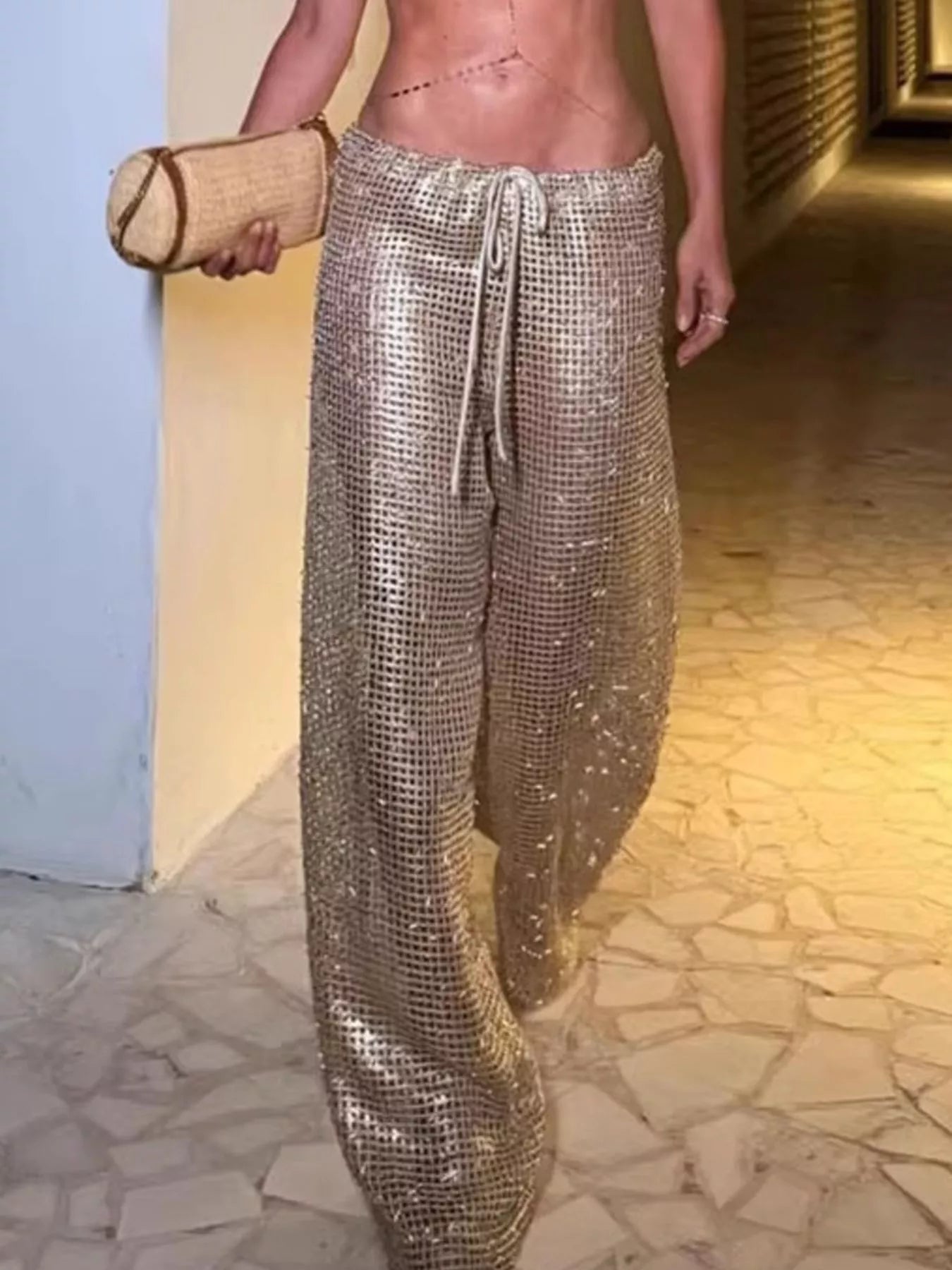 Person wearing sparkly gold pants walking on a stone pavement.