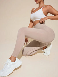 Person wearing a white sports bra and beige leggings on a beige background