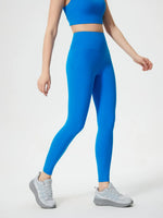 Person wearing blue athletic leggings and sports bra on a white background