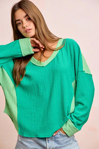 Woman wearing a green textured sweater against a plain background