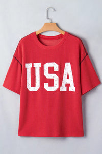 Red t-shirt with 'USA' print on a wooden hanger against a light gray background