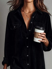 Person wearing a black shirt holding a coffee cup against a neutral background