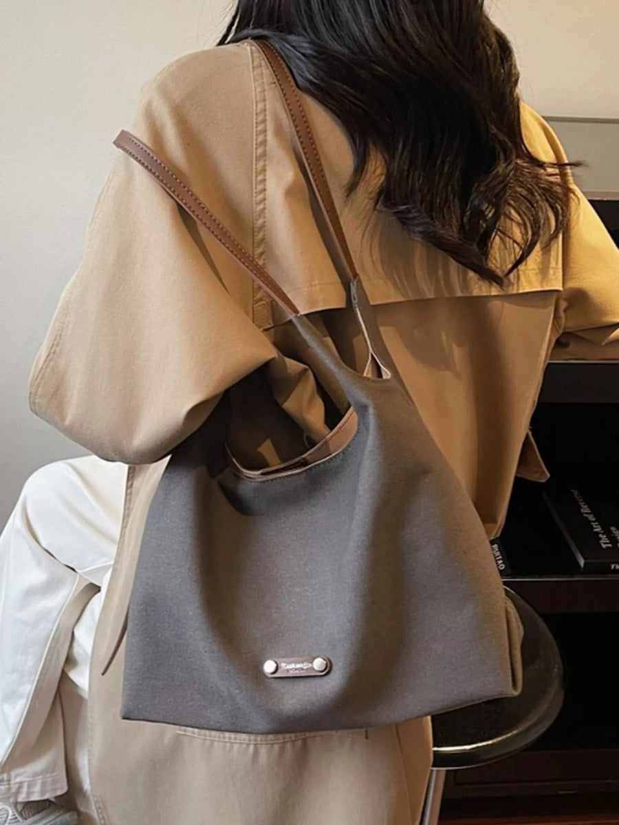 Person wearing a beige coat with a gray backpack, sitting in front of a piano.