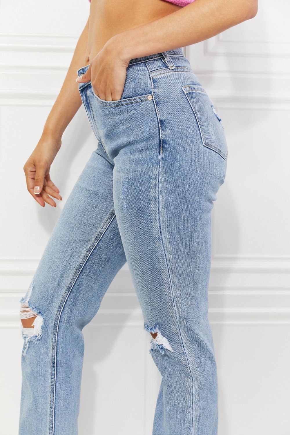 Light blue jeans with a distressed design worn by a person on a white background