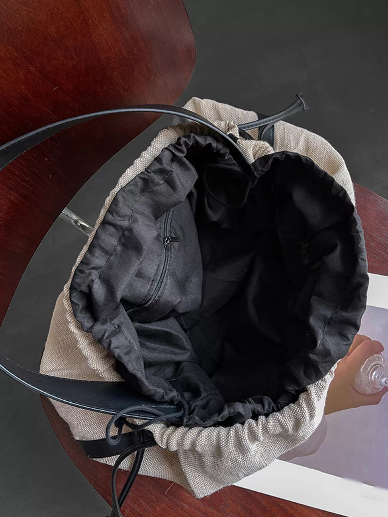 Close-up of a black bucket hat with beige interior on a wooden surface.
